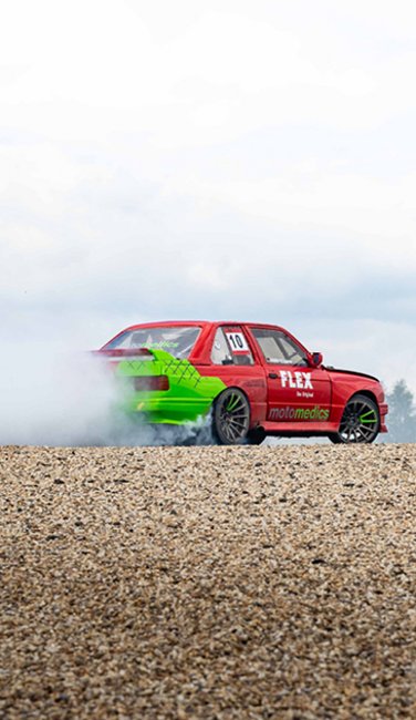VISUELL Blogbeitrag: Wir fotografieren und schreiben die Titelstory des DeinsMeinsUnsers, das Thema: Denise Ritzmann die Driftkönigin am Nürburgring VISUELL Blogbeitrag: Titelstory des DeinsMeinsUnsers: Ein driftendes rot/grünes Auto zieht eine Staubwolke hinter sich her