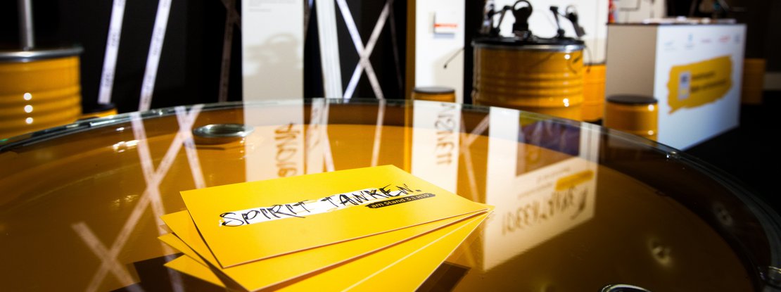 VISUELL Szenografie: Messestand für die MFG auf der Frankfurter Buchmesse VISUELL Szenografie: Messestand Ideentanke MFG: Detailaufnahme von vier gelben Flyern mit der Aufschrift Spirit tanken