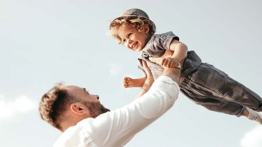 VISUELL Kommunikationsdesign: Corporate Design: Ein Vater hält seinen Sohn in den Himmel und beide freuen sich