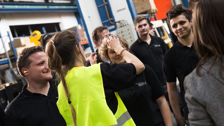 VISUELL Kommunikationsdesign: Kino-Werbespot „Wir haben das Zeug zum Heben!“ für STAHL CraneSystems VISUELL Kommunikationsdesign: Kino-Werbespot für STAHL CraneSystems: Eine Person aus dem Team richtet einer anderen Person die Haare