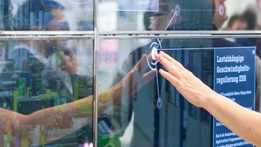 VISUELL Szenografie: Messestand STAHL CraneSystems: Nahaufnahme einer Hand, die den interaktiven Touchscreen der Medieninstallation bedient