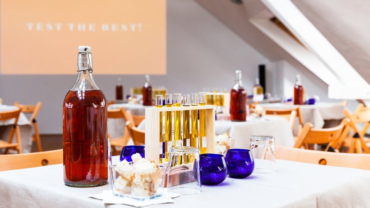 VISUELL Blogbeitrag: Das Event unterm Dach mit dem Thema „Taste the best“ – das Olivenöl-tasting. VISUELL Blogbeitrag: Event unterm Dach– das Olivenöl-tasting: Auf einem Tisch stehen verschiedene Arten Olivenöl in Reagenzgläsern