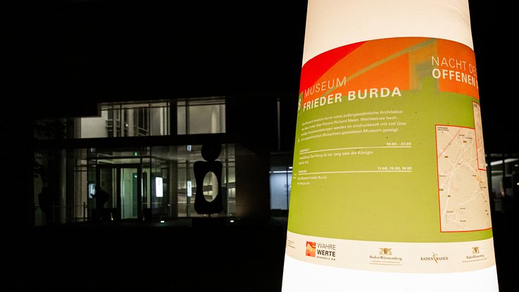 VISUELL Szenografie: Gestaltung und Realisierung des Leitsystems und der Printprodukte für die Nacht des offenen Denkmals in Baden-Baden. VISUELL Szenografie: Nacht des offenen Denkmals: Leitsystem-Leuchtkegel mit grüner Banderole - Aufschrift: Museum Frieder Burda
