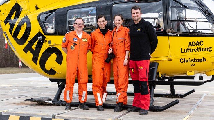 VISUELL Blogbeitrag: ADAC Luftrettung in Ulm mit dem Christoph 22: Claudia Reich mit Team und Laureen von VISUELL stehen vor dem gelben Helikopter Christoph 22