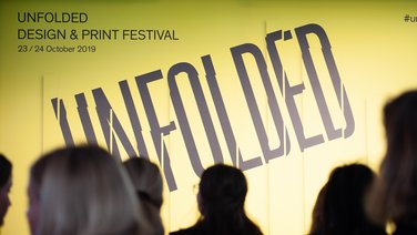 VISUELL Blogbeitrag: Weiterbildung in Innsbruck und München: Ein gelbes Plakat mit der Aufschrift UNFOLDED - Design und Print Festival