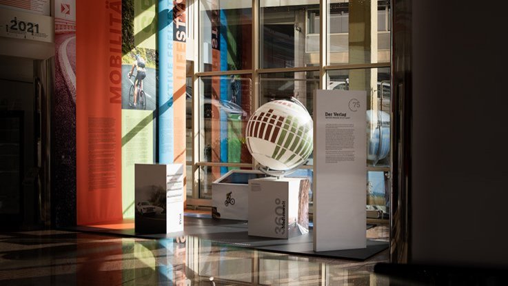 VISUELL Szenografie: Ausstellungsrundgang: Übersicht der Ausstellung, mit Stoffbannern und Globus für die Geschichte des Verlags 