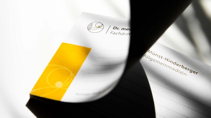 VISUELL Kommunikationsdesign: Corporate Design: Detail des Notizblocks mit Logo und gelbem grafischen Element sowie Linien für Schrift
