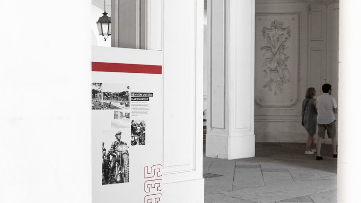 VISUELL Szenografie: Mythos Solitude am Schloss, die Ausstellung bei der Home and Garden VISUELL Szenografie: Solitude Ausstellung: Stoffbanner mit Bildern und Informationstext - Aufschrift: 1935, Rennen unterm Hakenkreuz