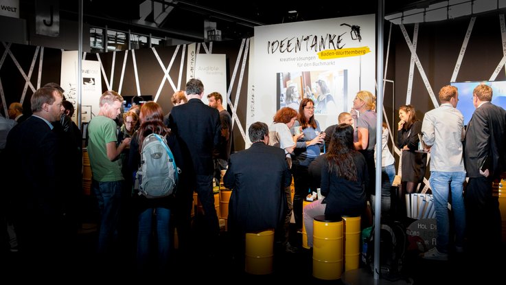 VISUELL Szenografie: Messestand für die MFG auf der Frankfurter Buchmesse VISUELL Szenografie: Messestand Ideentanke MFG: Gesamteindruck des Messestands mit zahlreichen Besuchenden