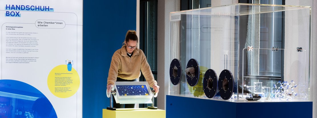 VISUELL Szenografie: Wissenschaftsausstellung „Was kann Katalyse?“ für den Sonderforschungsbereich SFB 1333 der Universität Stuttgart VISUELL Szenografie: Wissenschaftsausstellung: Eine Besucherin bedient eins der zwei interaktiven Exponate in der Ausstellung „Was kann Katalyse?“, daneben befindet sich eine Informationstafel mit Text und Bild