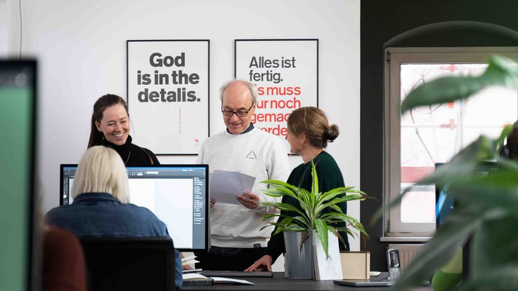 VISUELL Studio: 97a: Mitarbeiter stehen in einem Kreis und besprechen