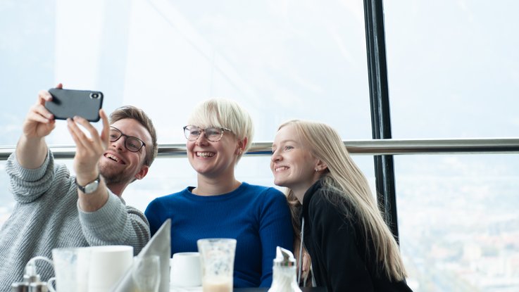 VISUELL Blogbeitrag: Weiterbildung in Innsbruck und München: Drei VISUELLerInnen machen auf Selfie im Restaurant des Olympiaturms