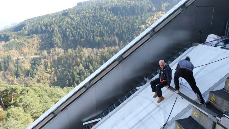 VISUELL Blogbeitrag: Weiterbildung in Innsbruck und München: Akex von VISUELL sitzt auf dem Zitterbalken der Bergisel­-Schanze