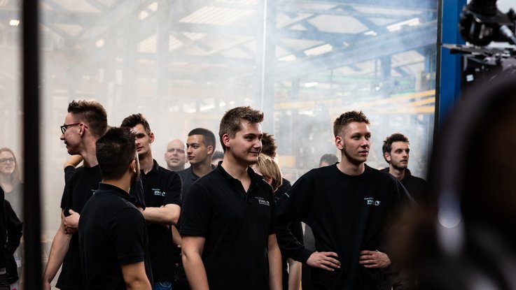 VISUELL Kommunikationsdesign: Kino-Werbespot „Wir haben das Zeug zum Heben!“ für STAHL CraneSystems VISUELL Kommunikationsdesign: Kino-Werbespot für STAHL CraneSystems: Eine Gruppe von Mitarbeitern im Werk von STAHL CraneSystems im dramatischen Nebel