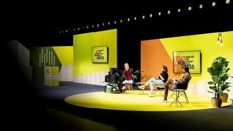 VISUELL Szenografie: Bühnenbild und Gesamtinszenierung vom AMS Kongress, Auto Motor und Sport, Motor Presse Stuttgart VISUELL Szenografie: Drei Personen unterhalten sich vor einer gelb/orangenen Wand