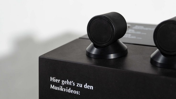 VISUELL Kommunikationsdesign: Hörstation mit der Aufschrift „Hier geht’s zu den Musikvideos“