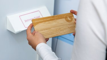 VISUELL Szenografie: die erste Escape-Ausstellung der Welt im StadtPalais Stuttgart – Museum für Stuttgart VISUELL Szenografie: Escape-Ausstellung: Ein Besucher hält das hölzerne Zeitreiseticket in der Hand, mithilfe dessen die Rätsel gelöst werden
