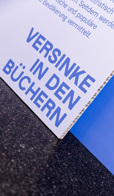 VISUELL Szenografie: 200 Jahre KOSMOS, Jubiläumsausstellung VISUELL Szenografie: Ausstellungsrundgang: Detailaufnahme blaue Texttafel – Aufschrift: Versinke in den Büchern