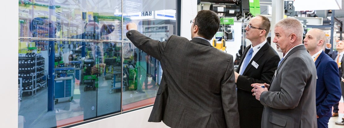 VISUELL Szenografie: Messestand STAHL CraneSystems: Vier Besucher bedienen die interaktive Medieninstallation über einen Touchscreen