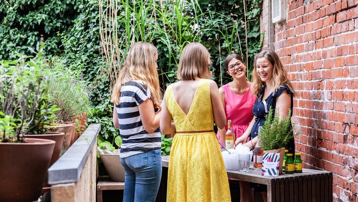 VISUELL Blogbeitrag: Das Event unterm Dach mit dem Thema „Taste the best“ – das Olivenöl-tasting. VISUELL Blogbeitrag: Event unterm Dach– das Olivenöl-tasting: Vier Frauen stehen im Hinterhof von VISUELL und unterhalten sich