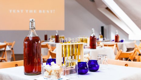VISUELL Blogbeitrag: Event unterm Dach– das Olivenöl-tasting: Auf einem Tisch stehen verschiedene Arten Olivenöl in Reagenzgläsern