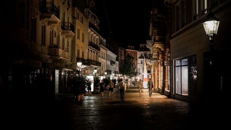 VISUELL Szenografie: Gestaltung und Realisierung des Leitsystems und der Printprodukte für die Nacht des offenen Denkmals in Baden-Baden. VISUELL Szenografie: Nacht des offenen Denkmals: Eine Seitengasse in Baden-Baden bei Nacht mit einem Leuchtkegel