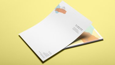 VISUELL Kommunikationsdesign: Visual Identity: Briefbogen mit gelber Rückseite und rote und blaue organische Farbfelder, sowie graue vereinzelte Punkte  
