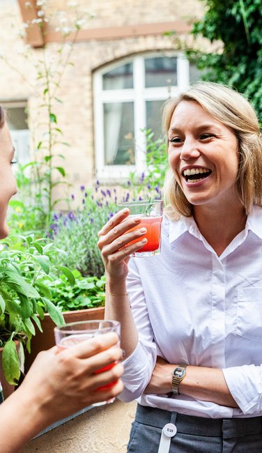 VISUELL Blogbeitrag: Das Event unterm Dach mit dem Thema „Taste the best“ – das Olivenöl-tasting. VISUELL Blogbeitrag: Event unterm Dach– das Olivenöl-tasting: Eine blonde Frau lacht mit einem Cocktail in der Hand