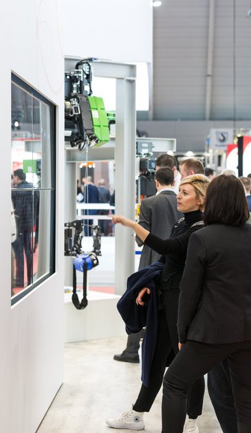 VISUELL Szenografie: Messestand STAHL CraneSystems: Zwei Besucherinnen stehen vor der interaktiven Medieninstallation