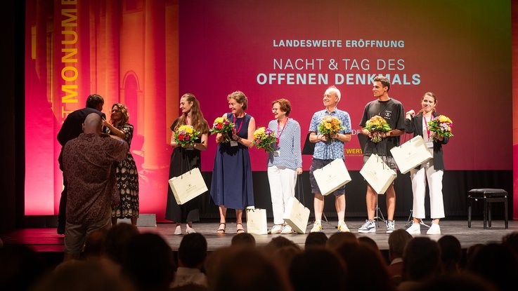 VISUELL Szenografie: Gestaltung und Realisierung des Leitsystems und der Printprodukte für die Nacht des offenen Denkmals in Baden-Baden. VISUELL Szenografie: Nacht des offenen Denkmals: Das VISUELL-Team wird bei der Auftaktveranstaltung auf die Bühne geholt