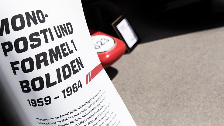 VISUELL Szenografie: Mythos Solitude am Schloss, die Ausstellung bei der Home and Garden VISUELL Szenografie: Solitude Ausstellung: Stoffbanner mit großer Aufschrift: Monofosti und Formel1 Boliden 1959-1964