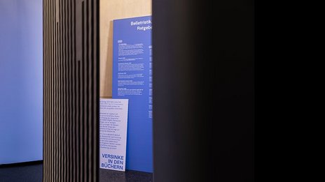 VISUELL Szenografie: 200 Jahre KOSMOS, Jubiläumsausstellung VISUELL Szenografie: Ausstellungsrundgang: zwei blaue Texttafeln – Aufschrift: Versinke in den Büchern